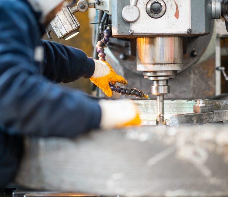 A worker in a factory working on a traditional milling machine A worker in a factory working on a traditional milling machine