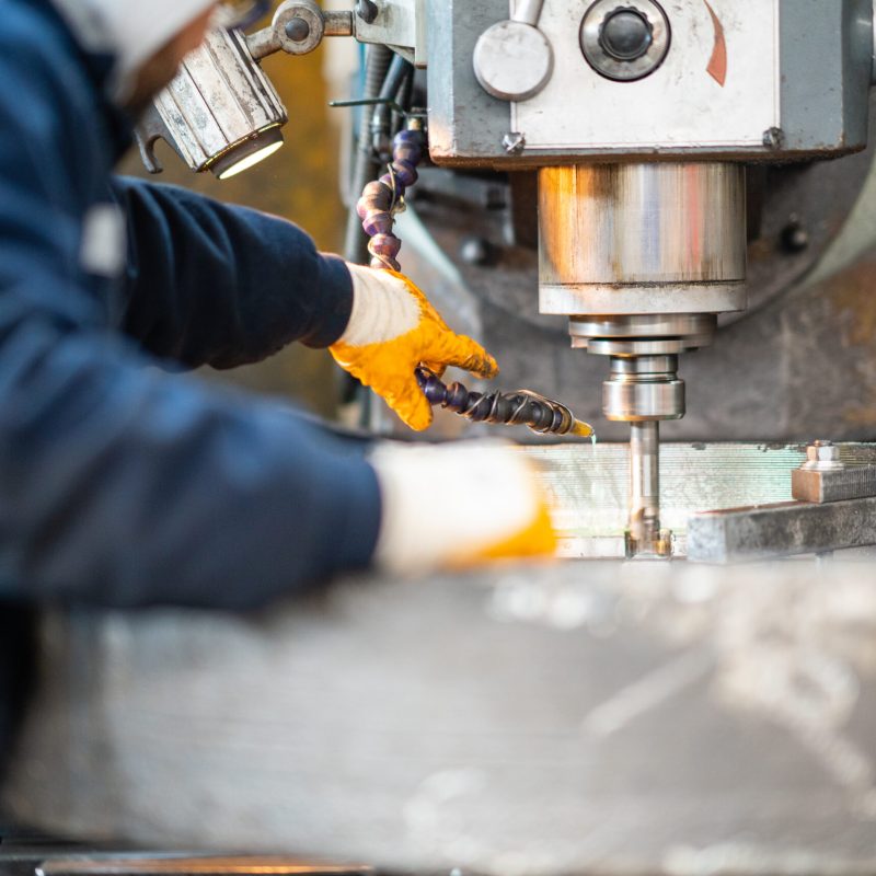 A worker in a factory working on a traditional milling machine A worker in a factory working on a traditional milling machine